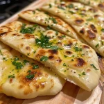 ['Close-up view of a golden-brown garlic flatbread on a rustic wooden table.', 'Side view of freshly baked air fryer garlic flatbread with a glossy garlic butter topping.', 'Juicy air fryer garlic flatbread displayed with herbs sprinkled on top.', 'Warm garlic flatbread cut into pieces, showcasing a crispy exterior and soft interior.']