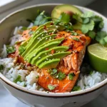 ['Close-up view of a colorful avocado salmon rice bowl with fresh ingredients.', 'Side view of a juicy avocado salmon rice bowl with vibrant toppings.', 'Detailed shot of a bowl featuring salmon, avocado, and cilantro over rice.', 'Close-up of a gourmet rice bowl with salmon, avocado, and lime garnish.']