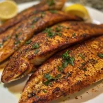 ['Close-up side view of crispy blackened tilapia on a white plate.', 'Juicy blackened tilapia fillets garnished with herbs and lemon slices.', 'Savory blackened tilapia served with a drizzle of olive oil and butter.', 'Vibrant display of blackened tilapia seasoned perfectly, ready to eat.']