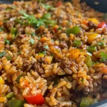 ['Close-up of a bowl of Cajun rice with ground beef and colorful vegetables.', 'Side view of juicy Cajun rice featuring minced chicken gizzards and bell peppers.', "Detailed shot of a serving of Popeye's-style Cajun rice, showcasing its rich textures.", 'Vibrant bowl of Cajun rice with garnished seasonings and ingredients visible.']