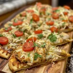 ['Close-up view of a Chicken Flatbread topped with melted cheese and vibrant vegetables.', 'Side angle of a Chicken Flatbread showcasing chicken, cheese, and colorful toppings.', 'Juicy Chicken Flatbread with diced tomatoes and cilantro, captured in detail.', 'Delicious Chicken Flatbread featuring golden-brown edges and fresh ingredients.']