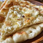 ['Close-up view of a golden-brown cottage cheese flatbread with a soft texture.', 'Side angle of a fluffy cottage cheese flatbread, showcasing its light and airy layers.', 'Appetizing cottage cheese flatbread, warm and freshly baked, resting on a wooden board.', 'Delicious, freshly made cottage cheese flatbread with visible cheese curds on the surface.']
