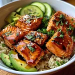 ['Close-up view of honey glazed salmon rice bowl with diced avocado and cucumber.', 'Side angle of a delicious honey glazed salmon bowl featuring fresh ingredients.', 'Juicy honey glazed salmon served over brown rice with garnishes of avocado and cilantro.', 'Colorful rice bowl with salmon, honey glaze, avocado, and cucumber, presented appetizingly.']