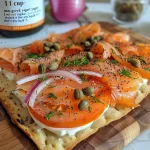 ['Close-up view of a smoked salmon breakfast flatbread topped with fresh ingredients.', 'Side view of a delicious flatbread featuring smoked salmon, cream cheese, and vegetables.', 'Juicy smoked salmon breakfast flatbread with vibrant toppings on a wooden surface.', 'Detailed shot of a flatbread with smoked salmon, red onions, capers, and dill.']