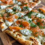 ['Close-up of a smoked salmon flatbread topped with ricotta cheese and herbs.', 'Side view of a juicy smoked salmon flatbread garnished with dill.', 'Detailed image of a naan flatbread layered with ricotta, smoked salmon, and cheese.', 'Close-up shot of a delicious flatbread with smoked salmon and mozzarella.']