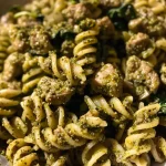 ['Close-up view of a bowl of Turkey Pesto Pasta garnished with fresh spinach.', 'Side view of a delicious serving of Turkey Pesto Pasta with ground turkey and colorful vegetables.', 'Juicy Turkey Pesto Pasta in a bowl, featuring a mix of pasta and vibrant greens.', 'Close-up photo of Turkey Pesto Pasta, highlighting the texture of the dish and the ingredients.']