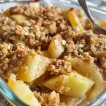 ['Close-up view of a golden brown Apple Crisp with visible apple slices and crumb topping.', 'Juicy Apple Crisp arranged in a baking dish, showcasing its rich, crispy topping.', 'Side view of freshly baked Apple Crisp, highlighting the texture of oats and spices.', 'A delicious Apple Crisp served warm, featuring a tantalizing crust and juicy apple layers.']