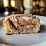 ['A close-up side view of a beautifully layered Cinnamon Roll Cake.', 'Juicy, decadent Cinnamon Roll Cake with visible swirls and glaze.', 'A detailed side shot of Cinnamon Roll Cake, showcasing its cinnamon filling and icing.', 'Lush Cinnamon Roll Cake with a glossy glaze, presented in a warm light.']