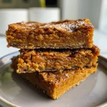 ['Close-up view of a slice of healthy pumpkin pie bar topped with chocolate chips.', 'Side view of healthy pumpkin pie bars with a golden crust and chocolate chips.', 'Delicious looking healthy pumpkin pie bars freshly baked, showcasing their texture.', 'Juicy pumpkin pie bars displayed with a warm, inviting appearance, featuring chocolate chips.']