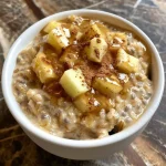 ['Close up of a bowl of High Protein Apple Cinnamon Overnight Oats with visible chopped apples and cinnamon.', 'Side view of Overnight Oats topped with chopped apples and a sprinkle of cinnamon.', 'Close up image showing creamy Overnight Oats with apple chunks and oats in a stylish bowl.', 'Detailed view of High Protein Apple Cinnamon Overnight Oats with a rich texture and fresh ingredients.']