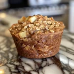 Close-up view of a golden-brown apple cinnamon protein muffin with a moist texture.