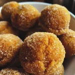 Close-up view of golden-brown baked pumpkin donut holes arranged on a plate.