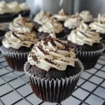 Close-up view of a Black Velvet Cupcake topped with a swirl of buttercream frosting and colorful sprinkles.