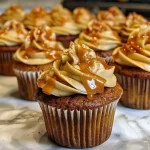 Side view of a caramel apple cupcake topped with caramel drizzle and apple slices.