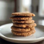 Close-up of a golden-brown cardamom cookie with a slightly cracked surface.