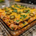 Close-up view of a juicy chicken enchilada casserole with layers of tortillas and cheese.