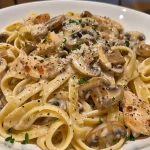 Close-up view of Chicken Mushroom Fettuccine, showing creamy sauce, sliced chicken, and mushrooms.