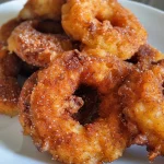 Close-up view of golden-brown cinnamon sugar apple fritters with a crispy exterior.