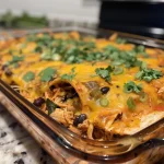 Close-up view of a delicious chicken enchilada casserole topped with cheese and herbs.