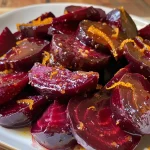 Close-up of vibrant roasted beet wedges glazed with maple syrup and garnished with fresh mint.