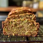 Close-up view of moist Protein Zucchini Bread with visible zucchini shreds and a golden crust.