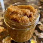 Close-up view of creamy pumpkin butter in a glass jar, with a spoon resting beside it.
